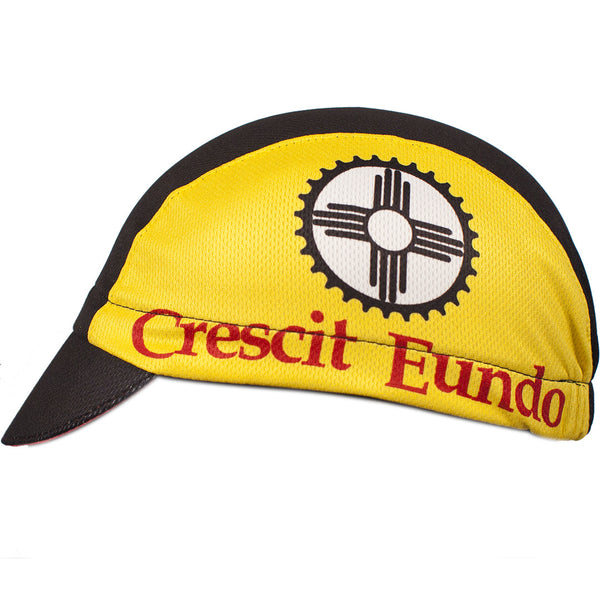 New Mexico 3-Panel Technical Cycling Cap.  Black and yellow cap with chilies on brim and New Mexico state flag print on side.  Crescit Eundo text on side.  Side view.