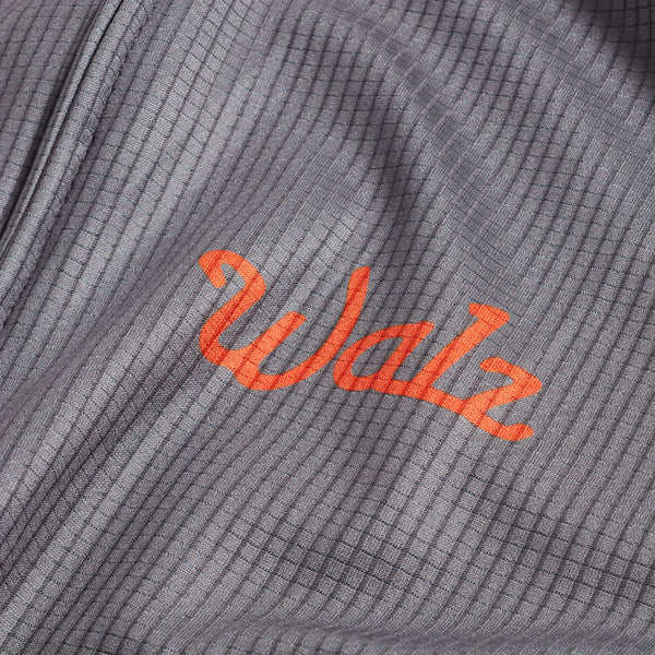 Close-up of orange Walz logo on gray fabric.