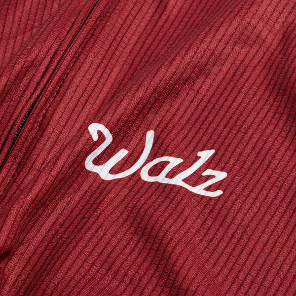 Close-up of white Walz logo with red fabric background.