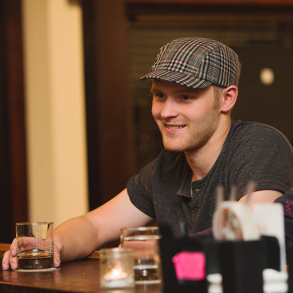 Man sitting at a bar wearing the velo/city plaid wool cap.