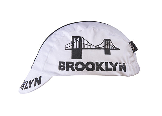 Brooklyn White Cotton 3-Panel Cycling Cap with Black Stripe.  Brooklyn bridge logo and Brooklyn text on side and brim. Side view.