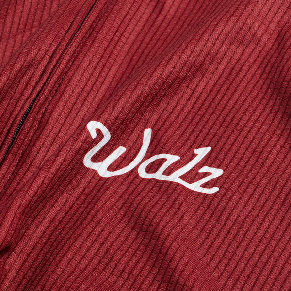 Close-up of white Walz logo with red fabric background.