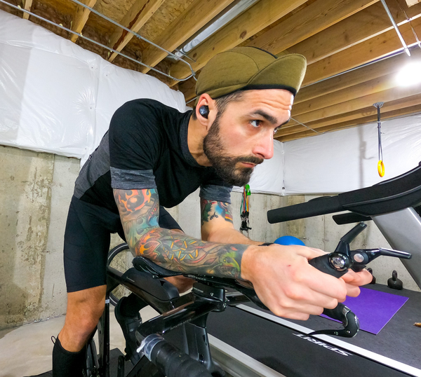 Man on stationary bike wearing the Army Olive Merino 3-Panel Cap.  Looking forward.