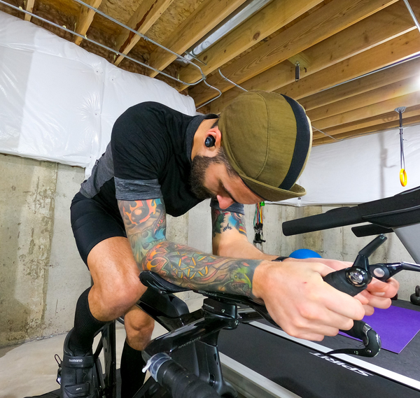 Man on stationary bike wearing the Army Olive Merino 3-Panel Cap.  Head down.