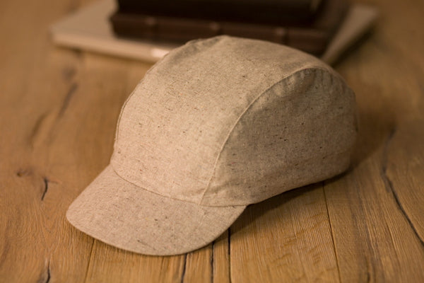 Velo/City Cap - Speckled Hemp Cap lying on a table next to some books.