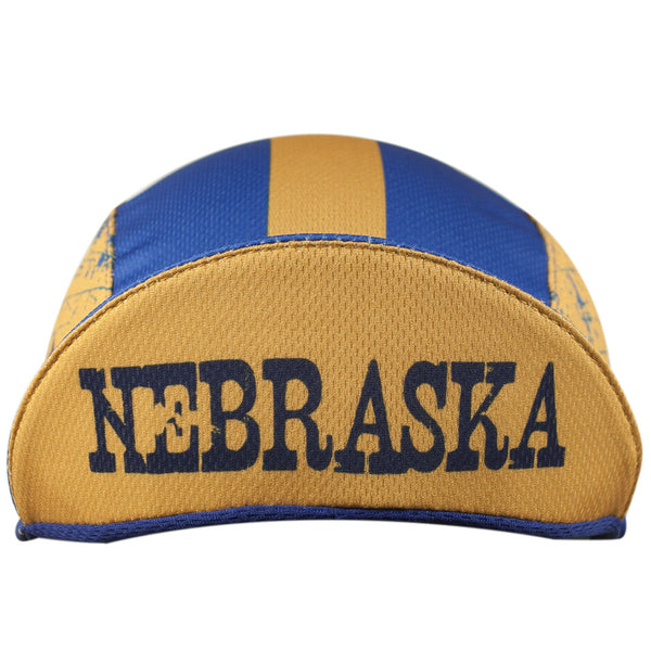 Nebraska Technical 3-Panel Cycling Cap. Blue and yellow cap with NEBRASKA text under brim.  Brim up front view.
