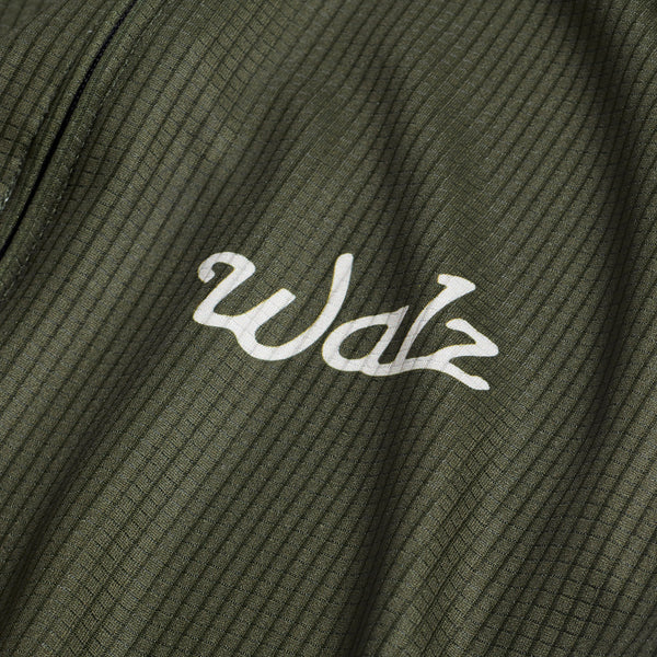 Close-up of white Walz logo on green fabric.