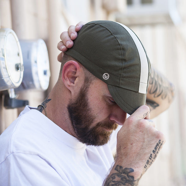 Man wearing woodland cap while holding brim.