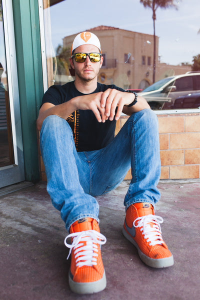 Man with orange shoes sitting down while wearing the Amy D. Foundation cycling cap.