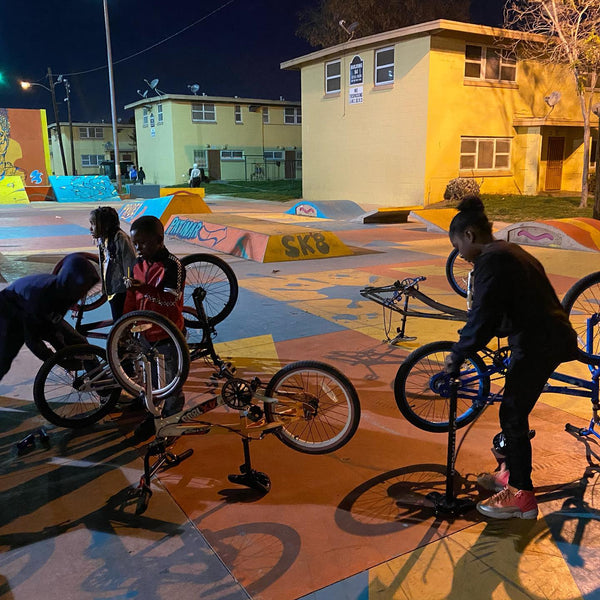 Kids working on bikes outside at night.