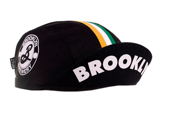Brooklyn Brewery Cotton 3-Panel Cycling Cap.  Black cap with Orange, White, and Green Stripes.  Brooklyn Brewery Logo on Side and Brooklyn text under brim.  Brim up angled view.