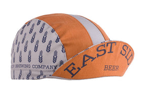 Next Door Brewing Cotton 3-Panel Cycling Cap.  Orange and white cap with Next door Brewing company print on side and East Side Beer text under brim.  Brim up angled view.